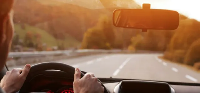 driver looking forward towards the road with their eyes reflected in the rearview mirror